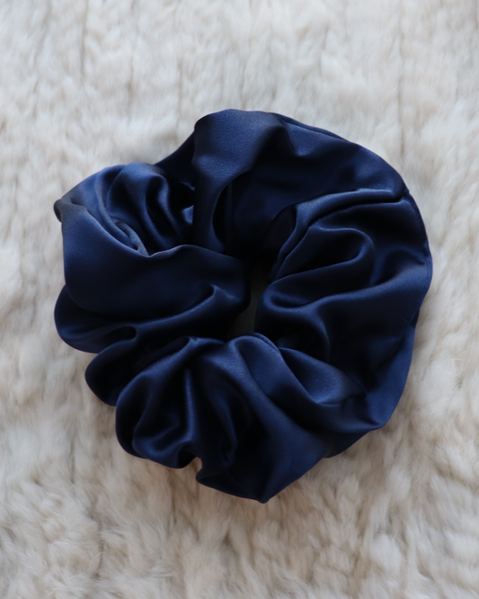 Single top-down view of a Midnight Navy mulberry silk scrunchie, highlighting its smooth, luxurious folds and deep color. Perfect for all hair types.