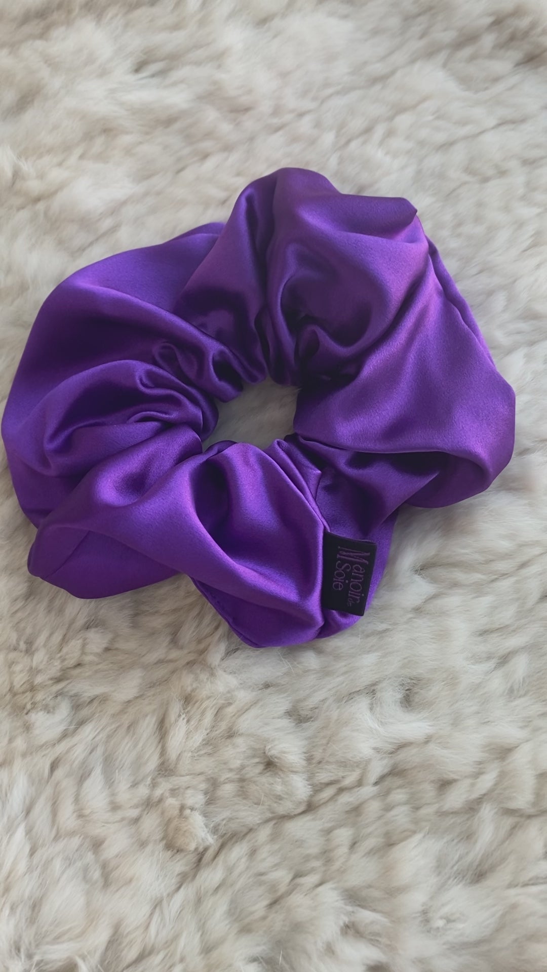 Video demonstrating the Royal Purple mulberry silk scrunchie as it is flipped to show both sides, highlighting its smooth texture, elegant drape, and consistent luxurious appearance from all angles.