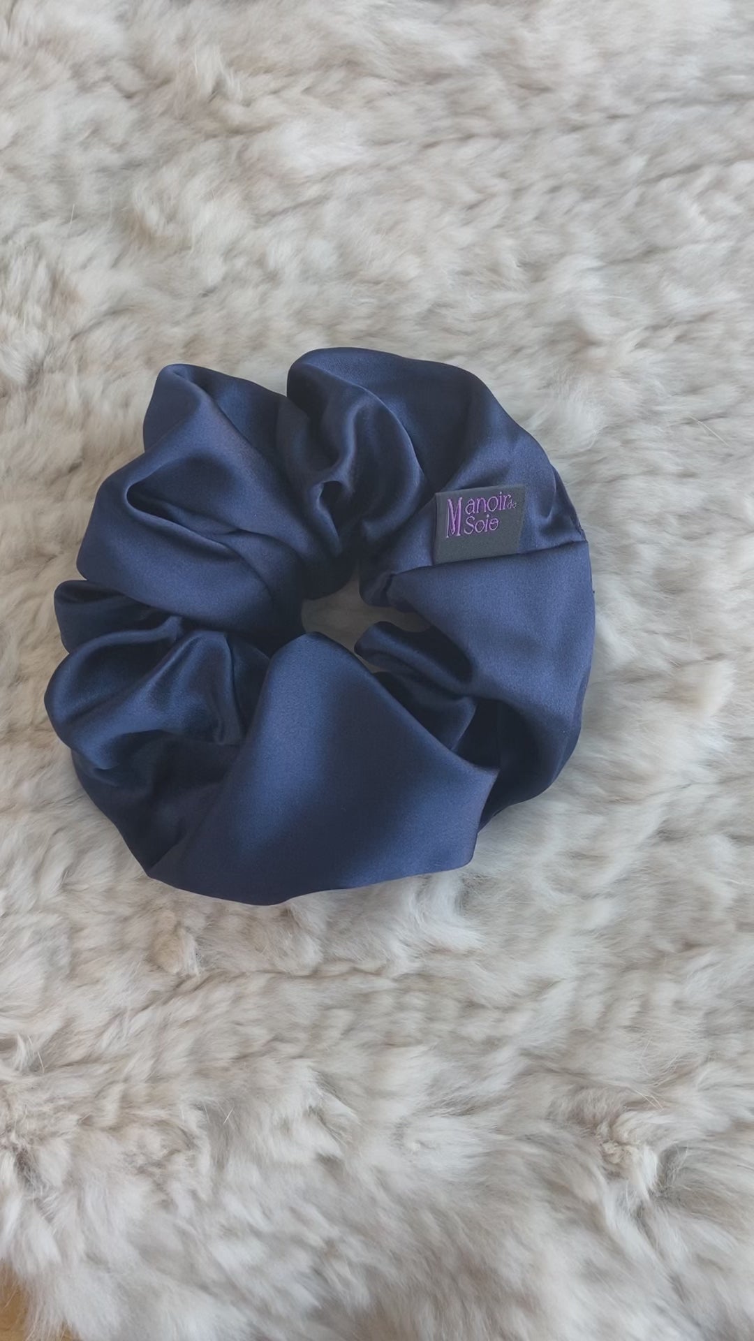 Video demonstrating the Midnight Navy mulberry silk scrunchie as it is flipped to show both sides, highlighting its smooth texture, elegant drape, and consistent luxurious appearance from all angles.