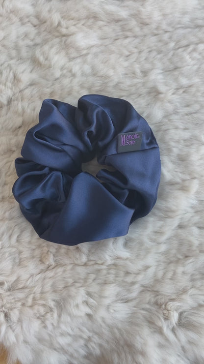 Video demonstrating the Midnight Navy mulberry silk scrunchie as it is flipped to show both sides, highlighting its smooth texture, elegant drape, and consistent luxurious appearance from all angles.